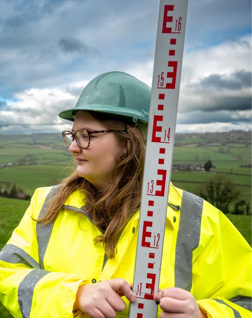 Person standing in field with measuring tool