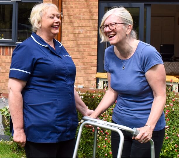 Care worker assisting a member of community using a walking frame
