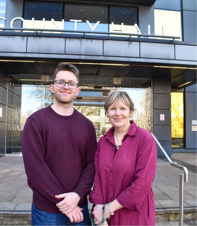 Two people smiling in front of building